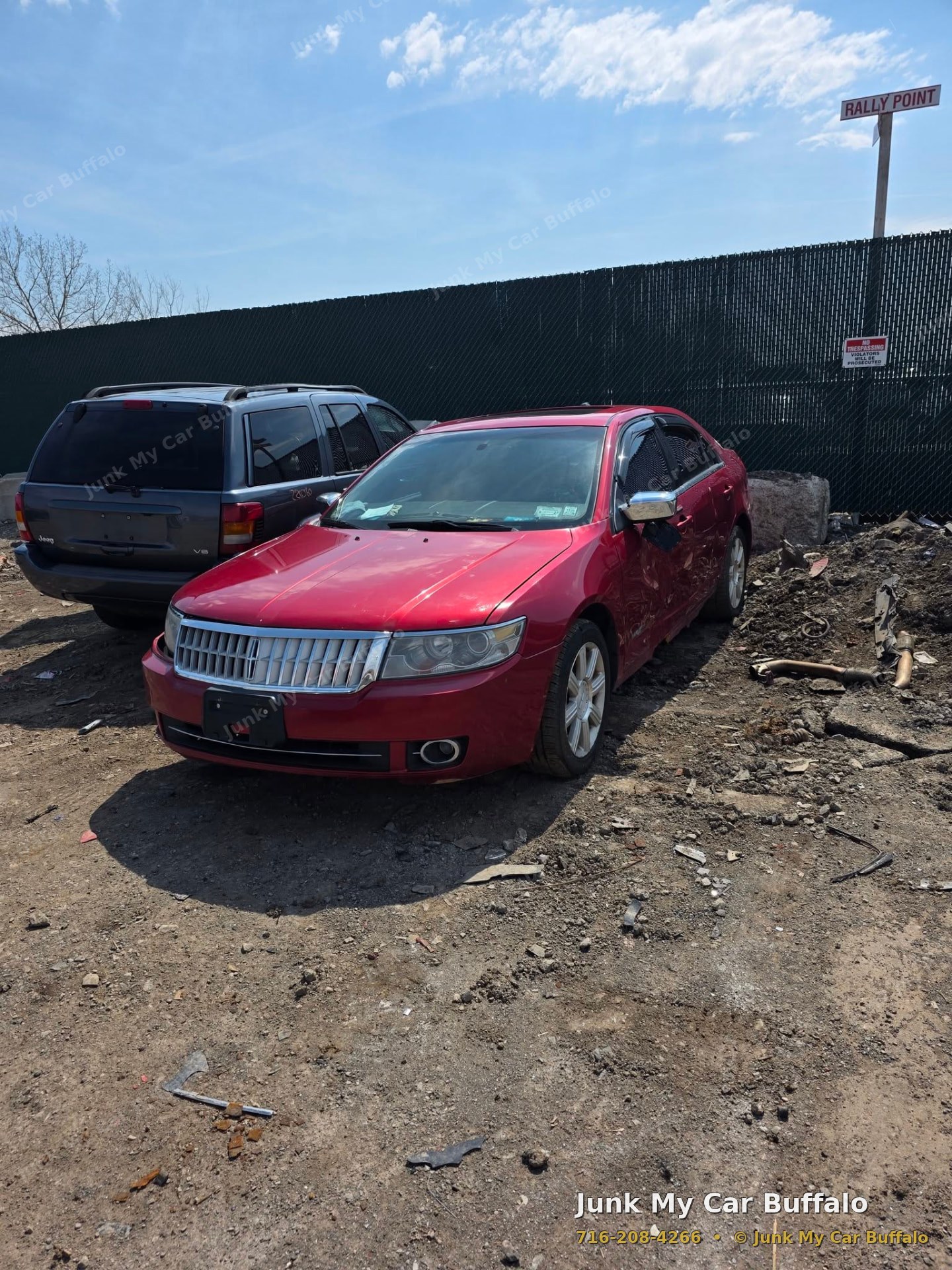 Damaged red sedan with body damage sitting in a Buffalo salvage yard