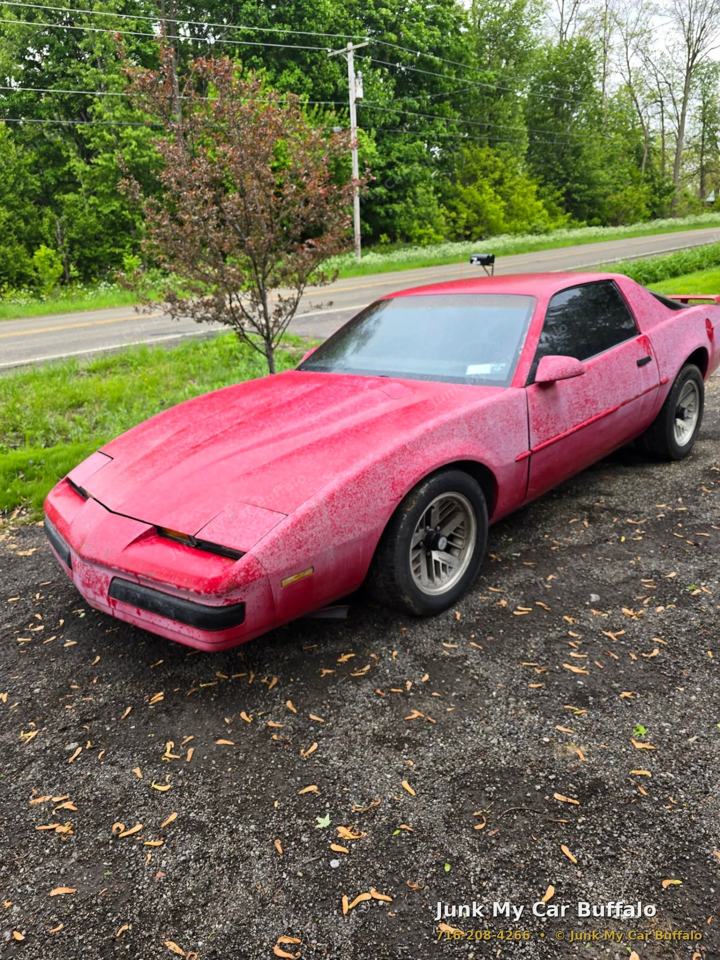 Faded red non-running sports car parked on gravel awaiting pickup