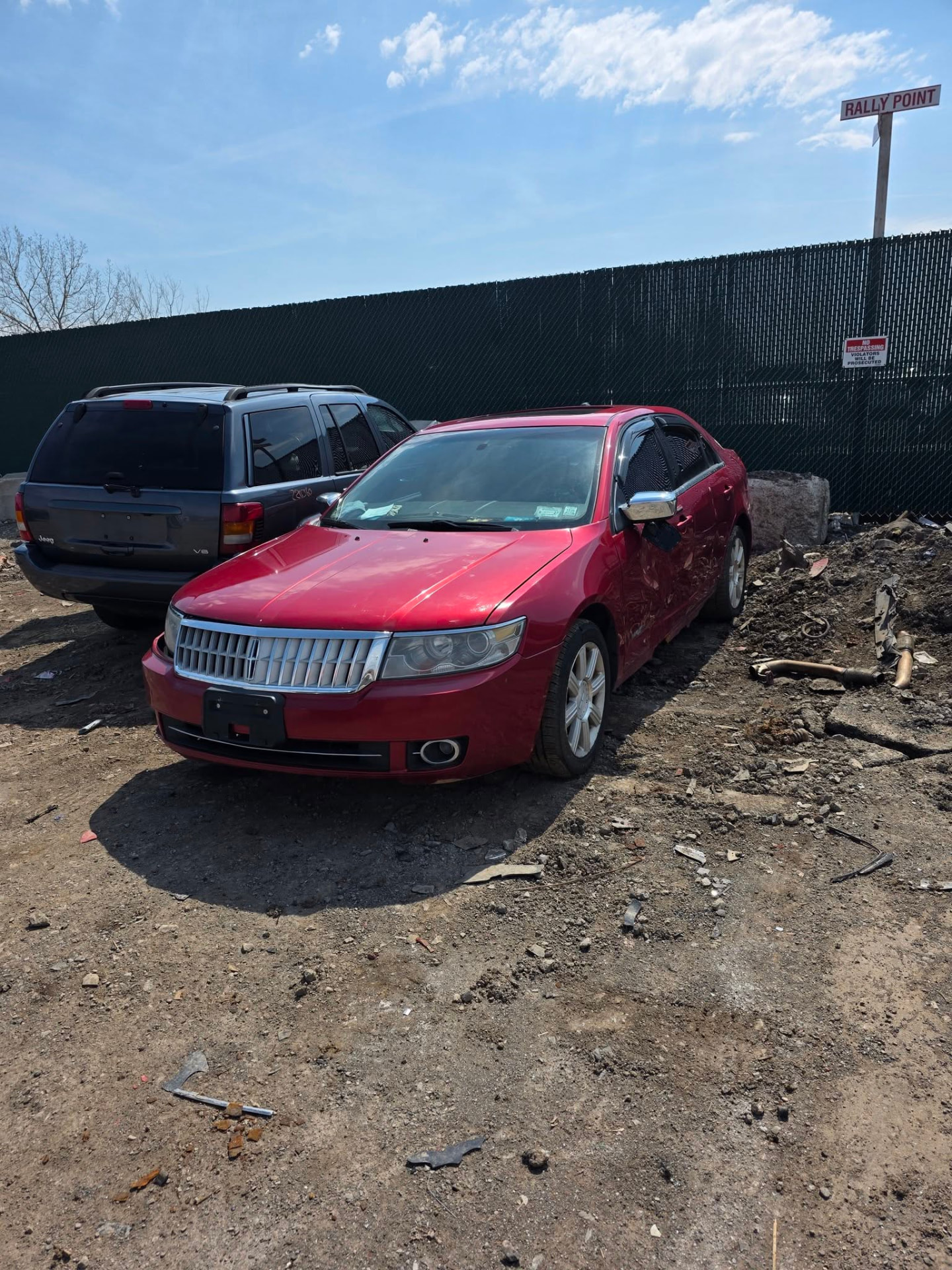 Damaged red sedan with body damage sitting in a Buffalo salvage yard